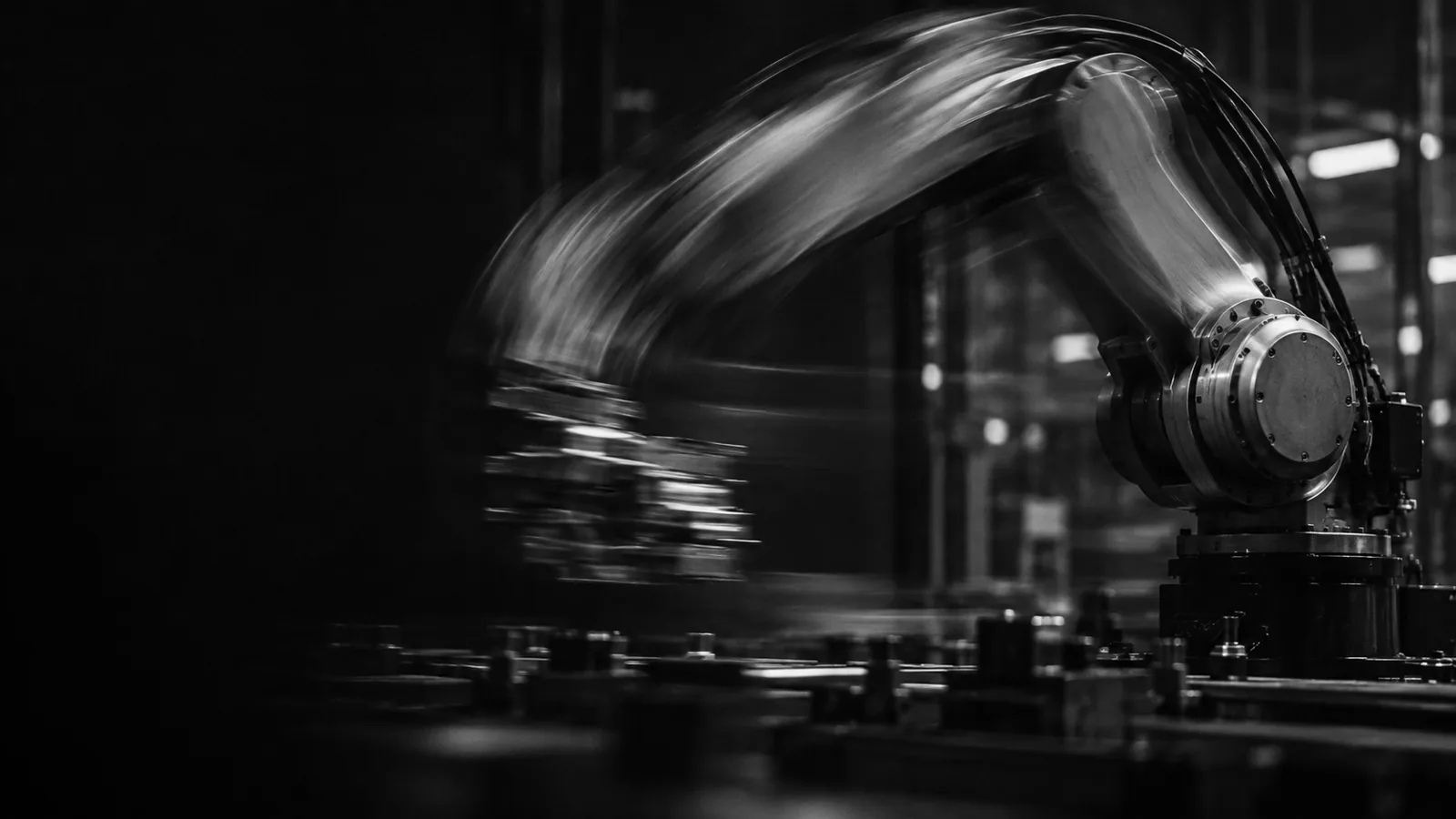 An industrial robot arm in motion, blurred, in black and white